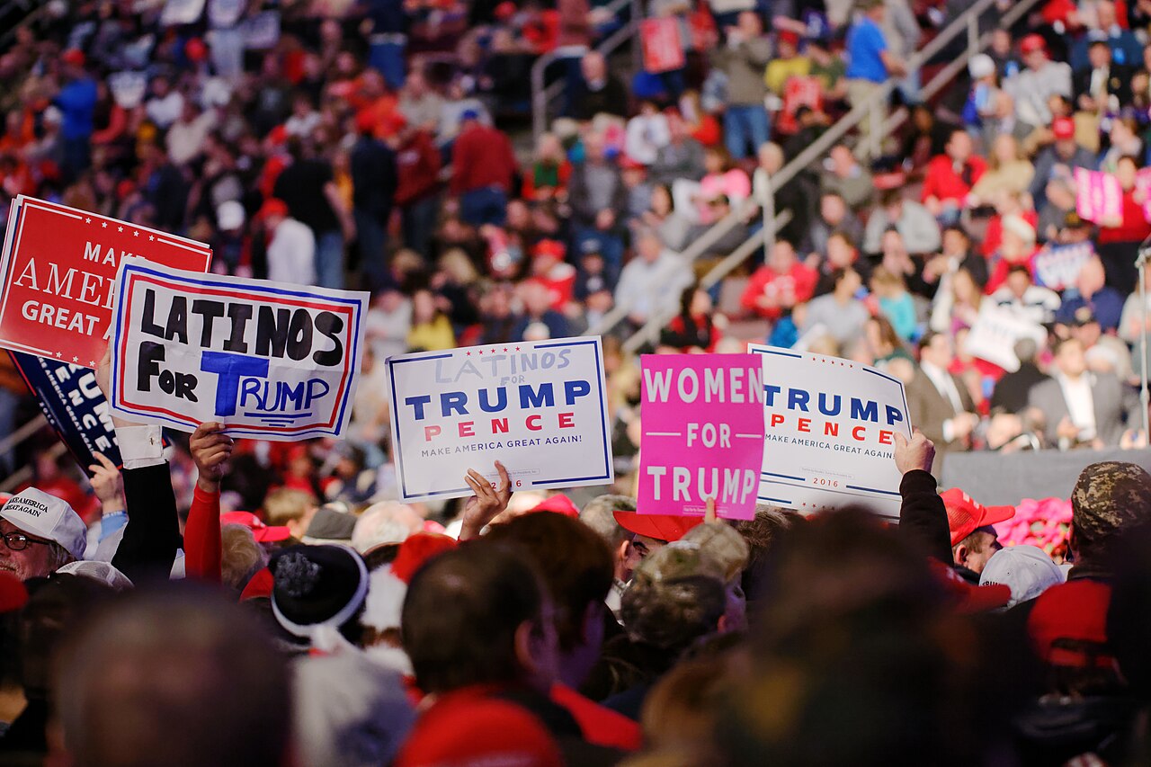 A group of Donald Trump supporters at a rally hold signs in favor of him.