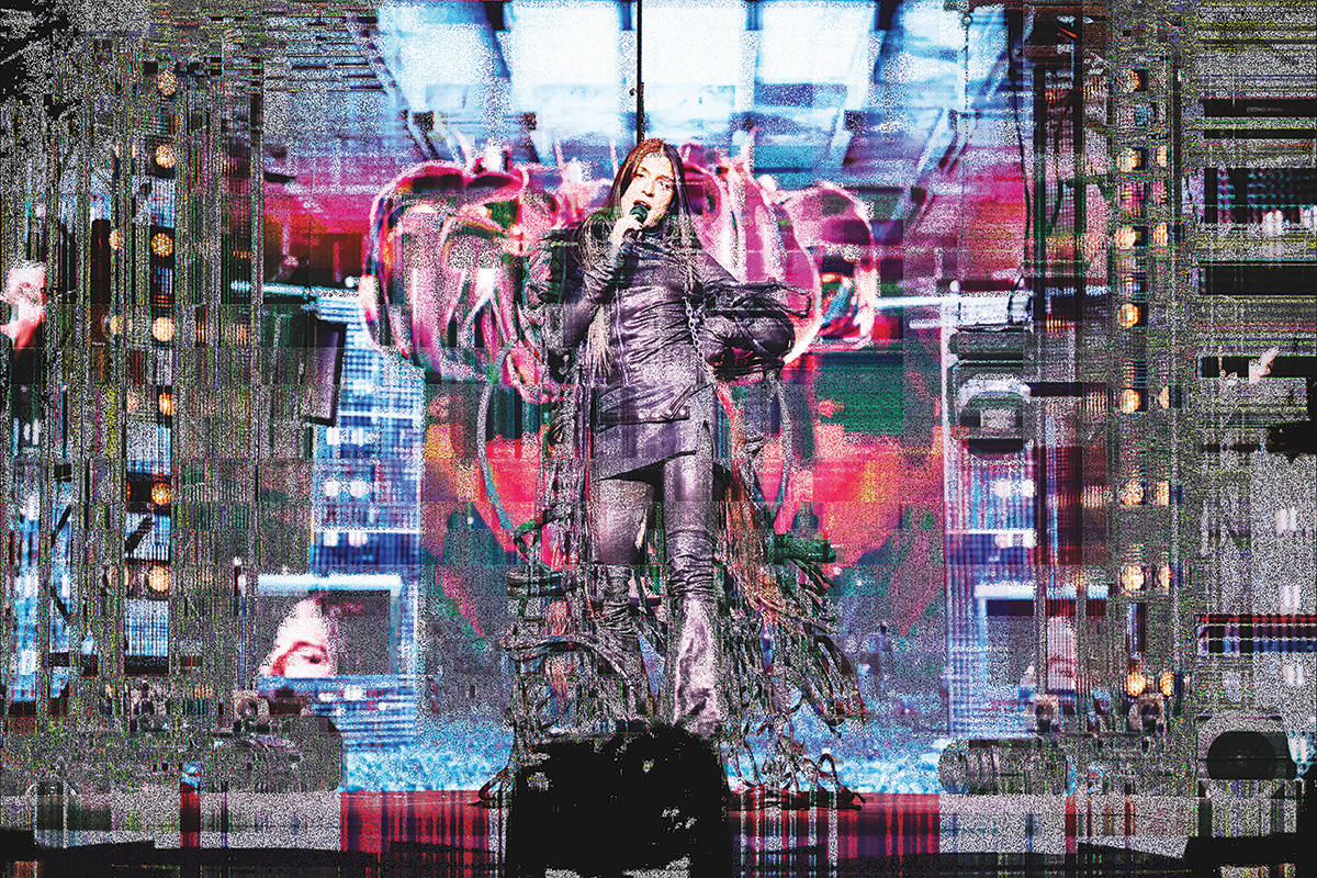 A distorted, pixelated, static-y image of Arca performing on stage