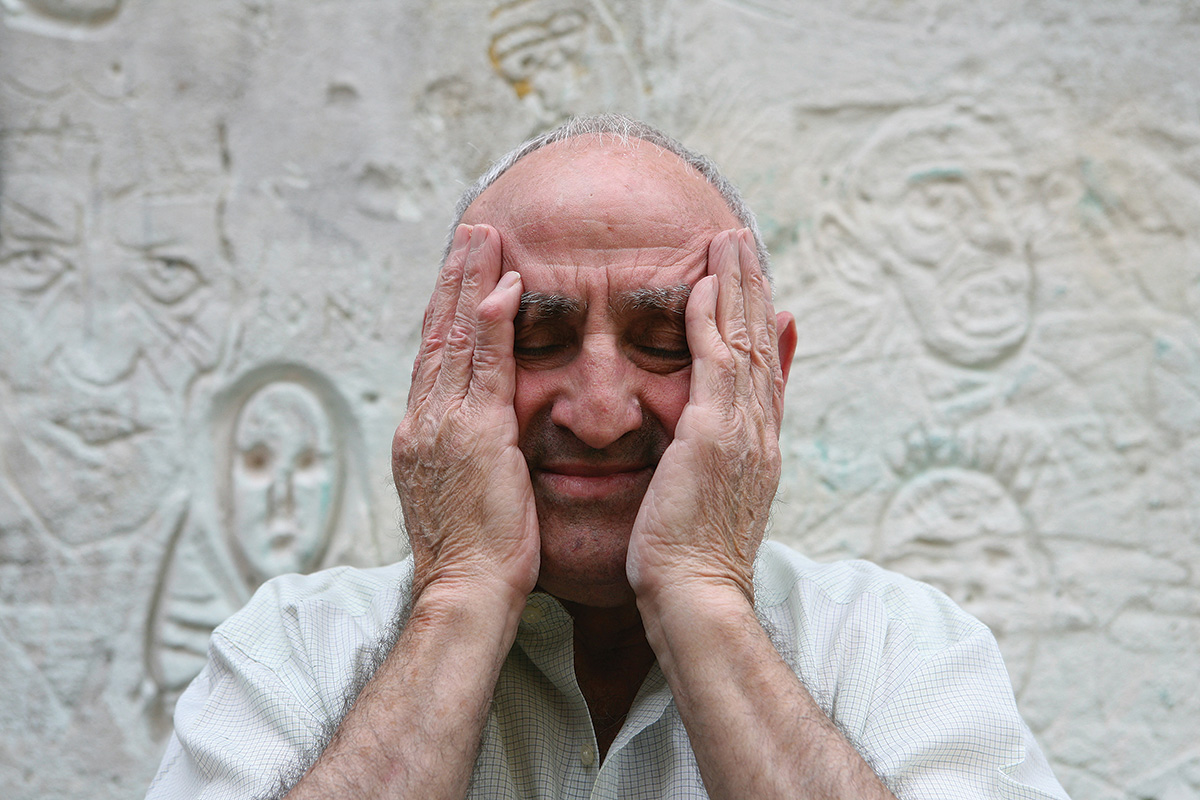 An elderly Lucio Urtubia cupping his face with his palms